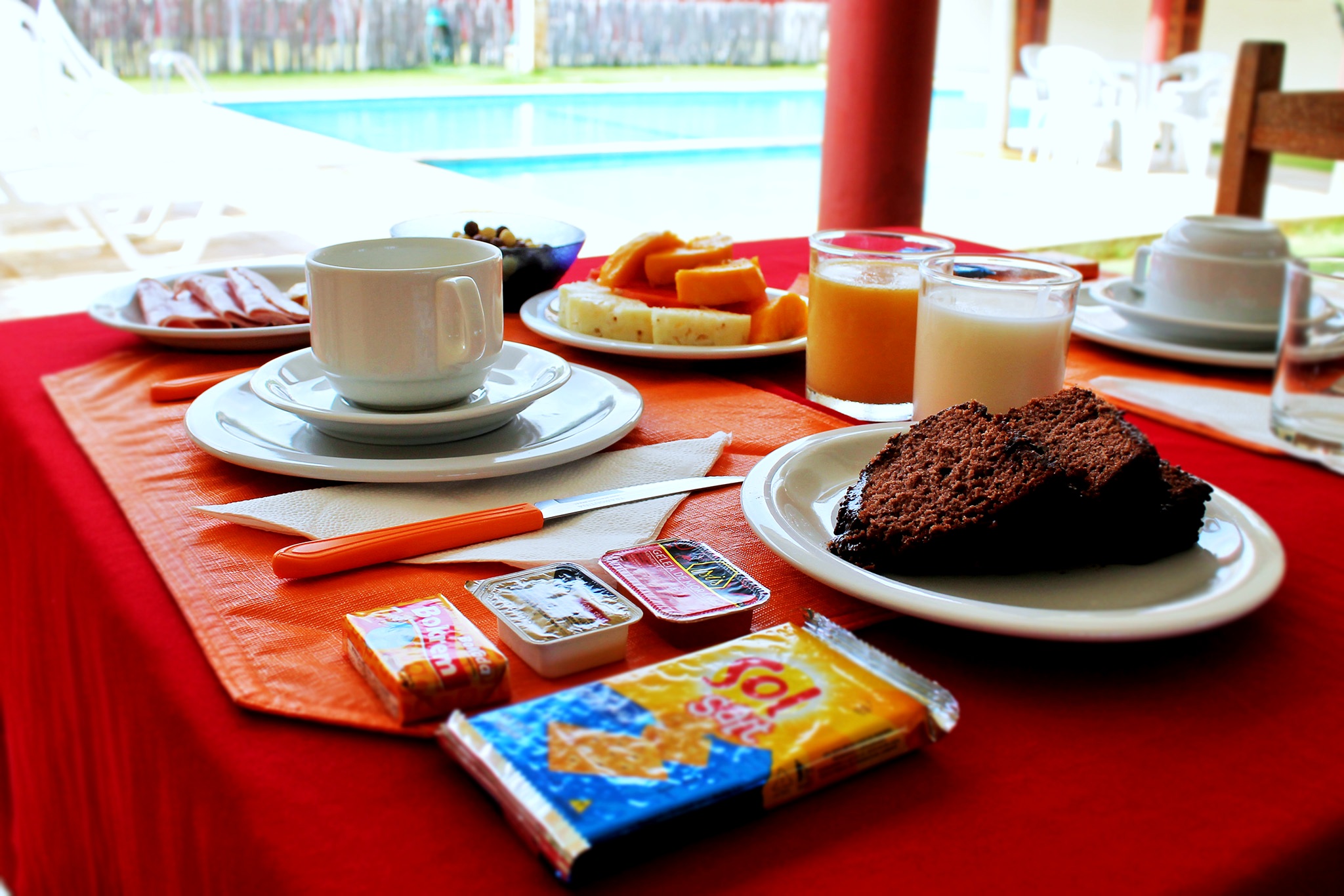 Mesa de café da manhã servida na varanda arejada com vista para a piscina